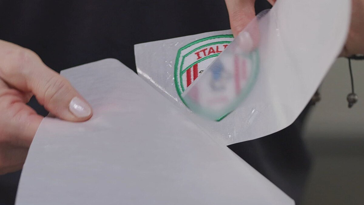 embroiderer holding a badge with heat seal film to fif the badge onto a garment