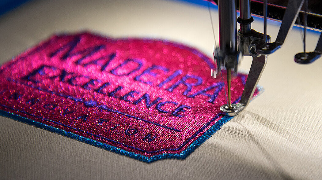 Shiny pink metallic thread emboirdery badge on a machine