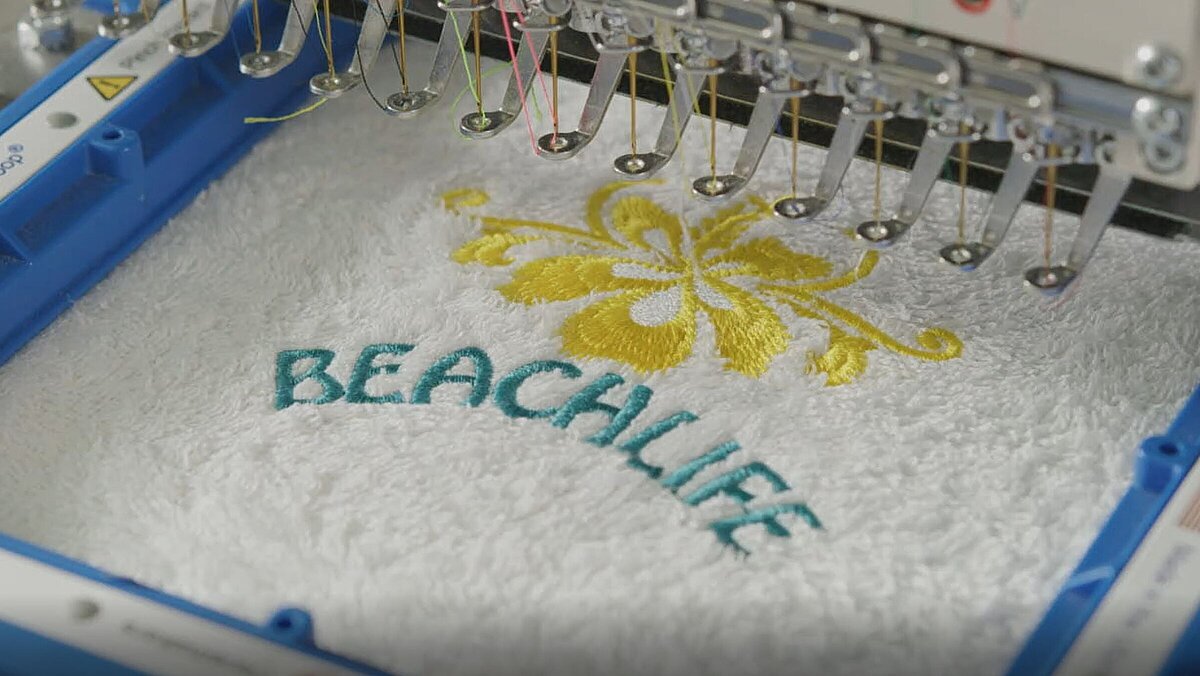 Terrycloth towel with a yellow flower and the word Beachlife on an embroidery machine