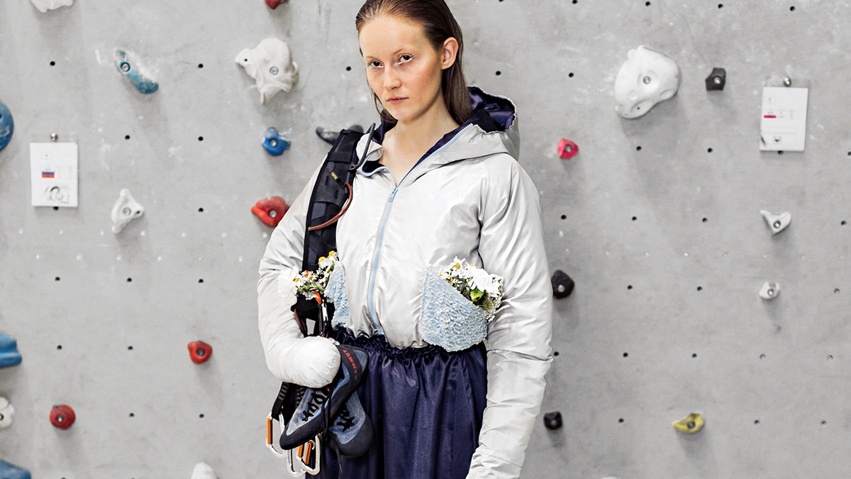 Girl in embroidered outdoor fashion clothes in front of hiking wall