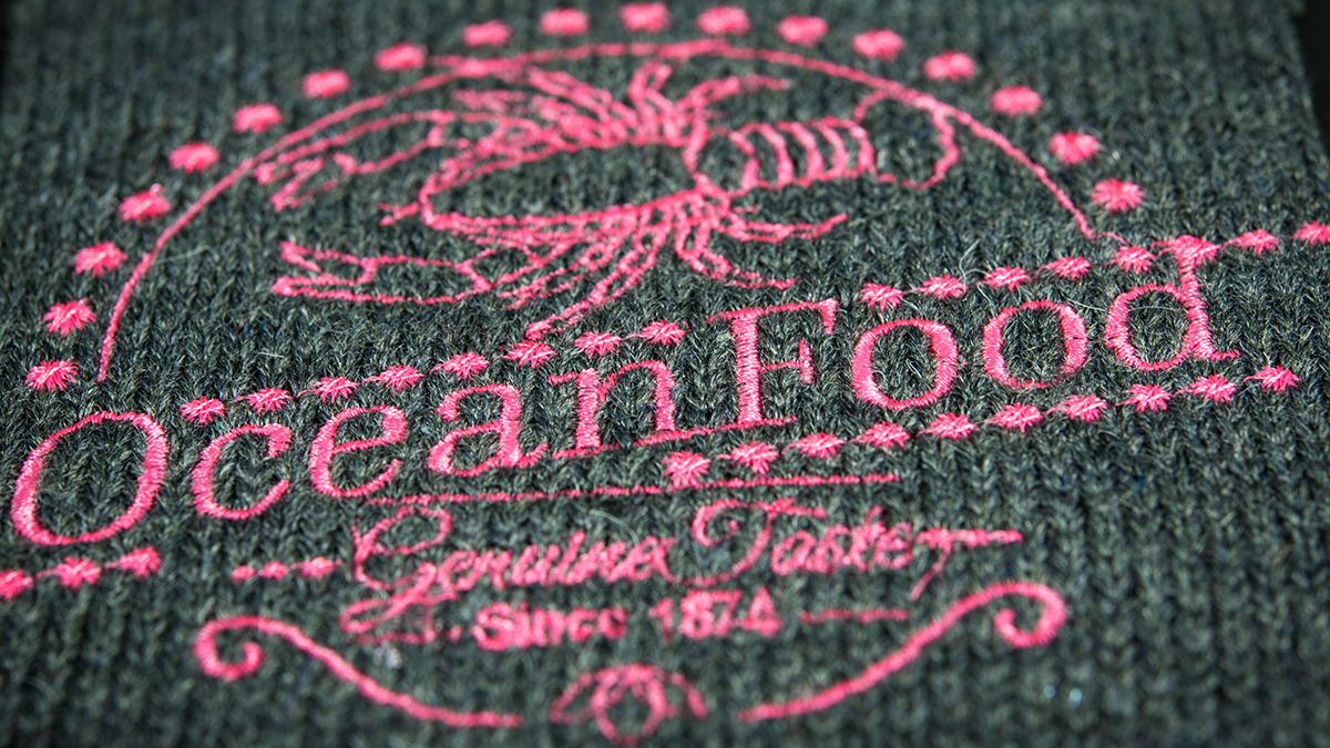 pink embroidered logo on grey woven fabric